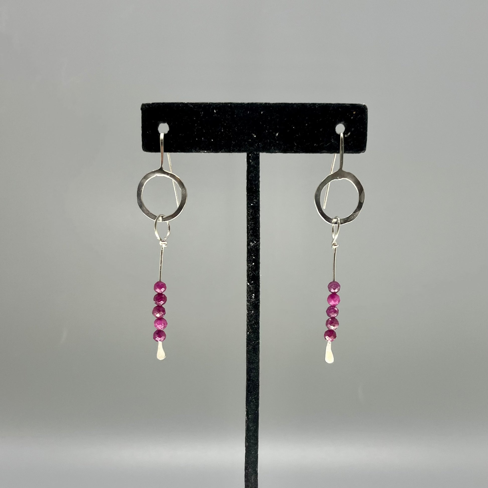 Sterling silver dangle earrings consisting of a hoop of silver and a dangle with 5 rubies 3mm each. Rocking Glass Studio