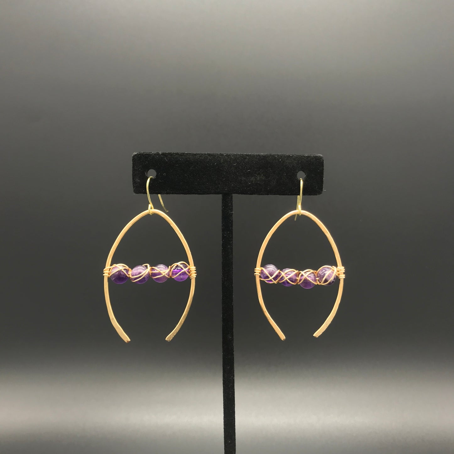 Amethyst earrings in gold colored wishbone shaped wire. Rocking Glass Studio